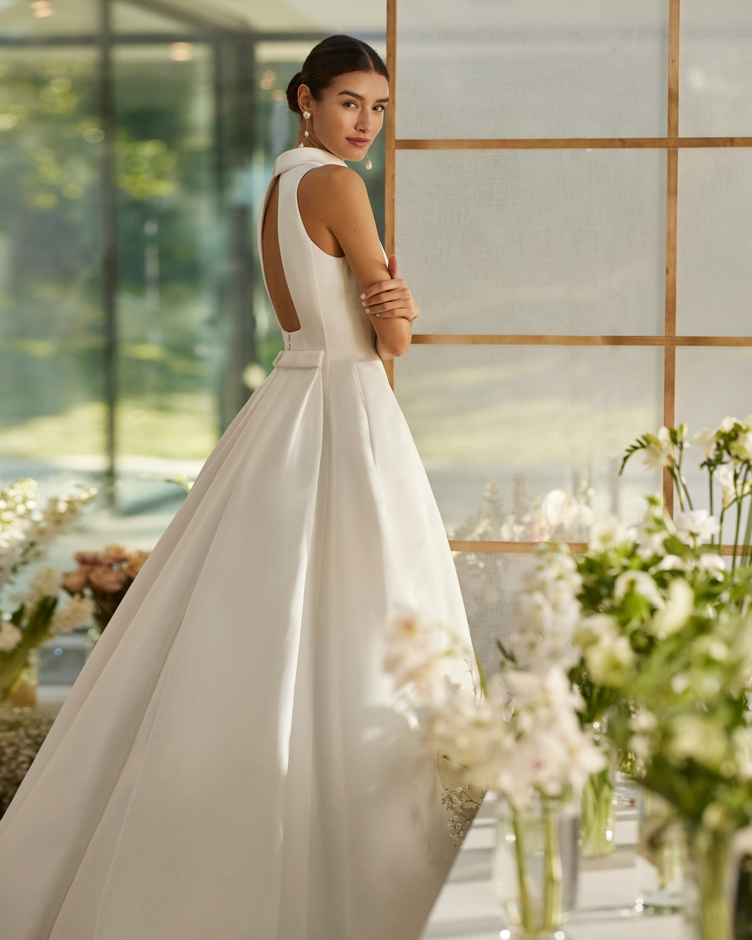 Vestido de noiva de duas peças, com corte em A e estilo elegante, elaborado com cetim. Este modelo sem mangas mostra uma gola alta, costas abertas e uma cauda removível de cetim. Um modelo exclusivo Rosa Clará Couture.