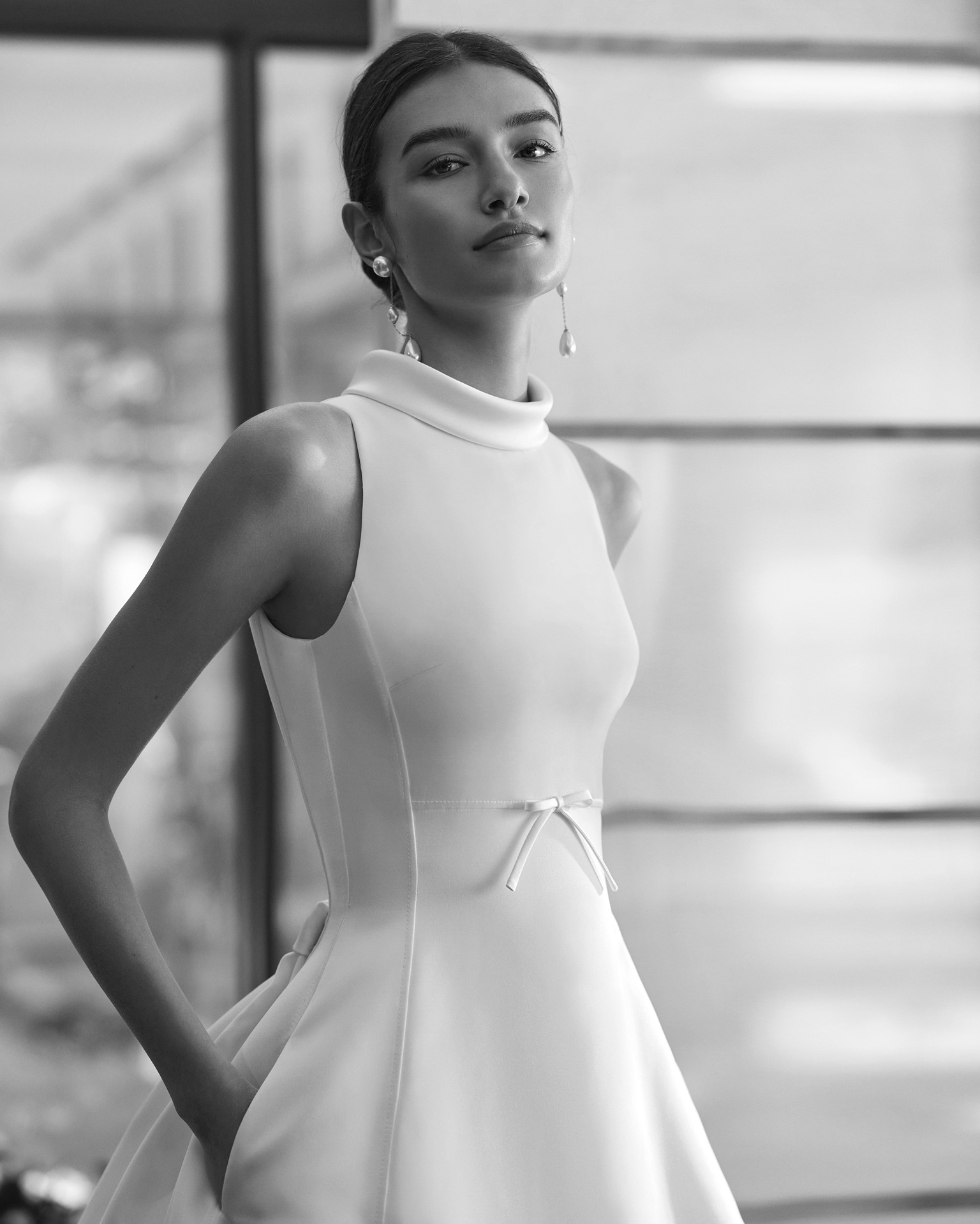 Vestido de noiva de duas peças, com corte em A e estilo elegante, elaborado com cetim. Este modelo sem mangas mostra uma gola alta, costas abertas e uma cauda removível de cetim. Um modelo exclusivo Rosa Clará Couture.