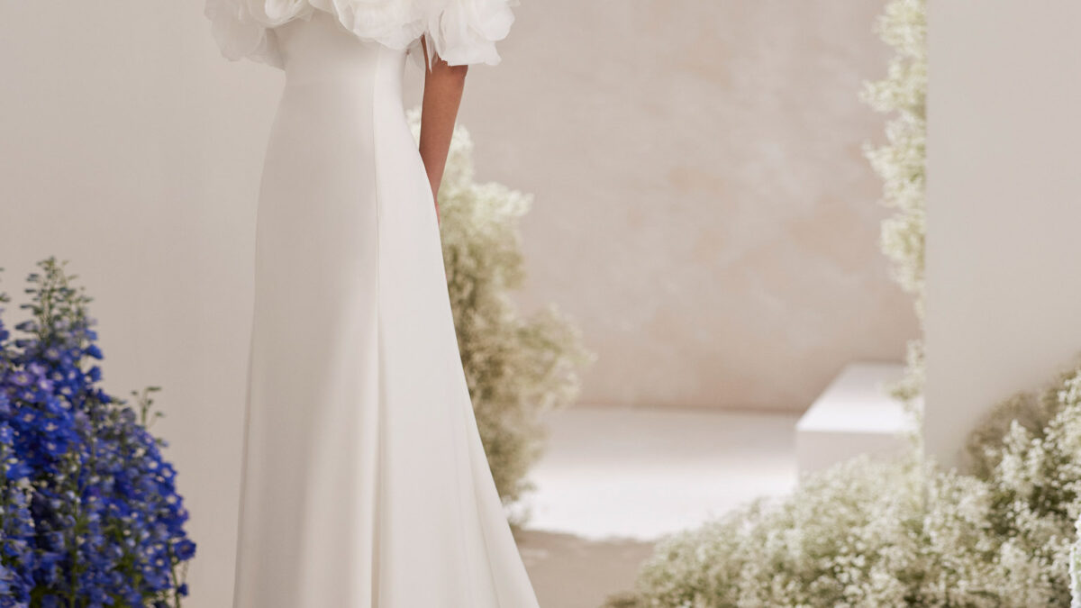 Vestido de noiva de duas peças, corte direito e estilo romântico, confecionado com crepe. Apresenta um decote caicai e uma gola removível com flores de organza. Exiba um delicado modelo Rosa Clará Couture