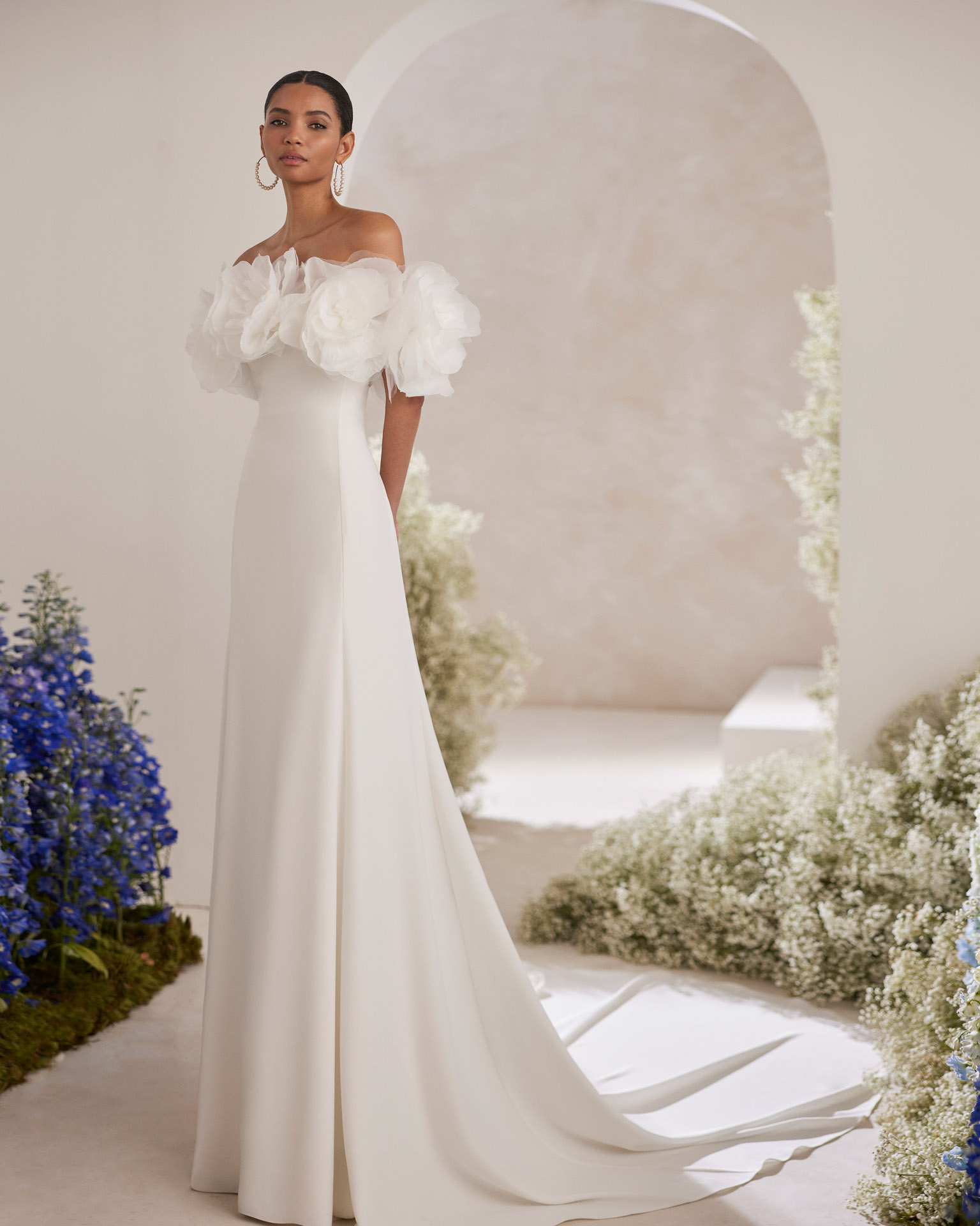 Vestido de noiva de duas peças, corte direito e estilo romântico, confecionado com crepe. Apresenta um decote caicai e uma gola removível com flores de organza. Exiba um delicado modelo Rosa Clará Couture