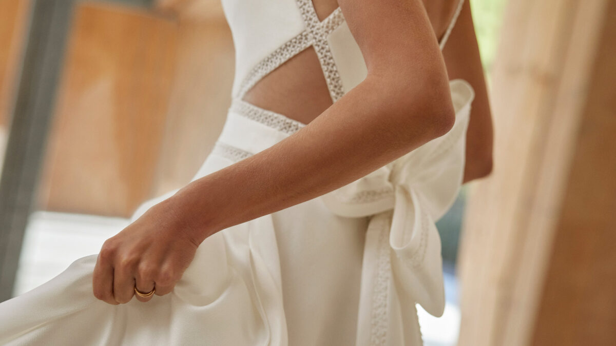 Vestido de noiva com corte em A e estilo clássico, realizado em mikado combinado com renda e brilhantes. Completa-se com um decote barco, umas costas abertas e alças. Um fato de noiva Rosa Clará.