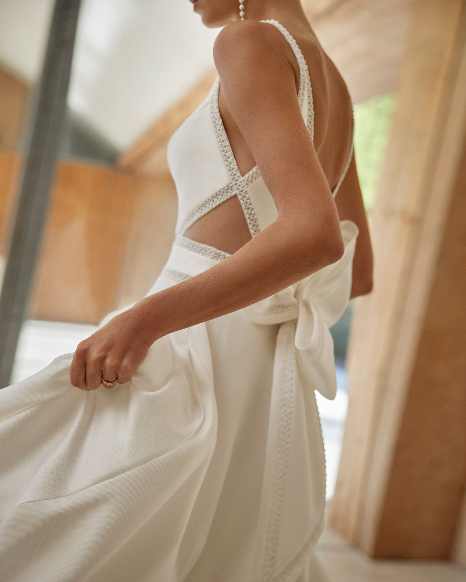 Vestido de noiva com corte em A e estilo clássico, realizado em mikado combinado com renda e brilhantes. Completa-se com um decote barco, umas costas abertas e alças. Um fato de noiva Rosa Clará.