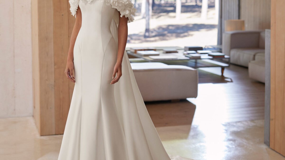 Vestido de noiva de três peças, de corte sereia e estilo romântico, confecionado em mikado elástico. Mostra um decote caicai, uma gola envolvente removível e uma cauda removível. Um conjunto exclusivo Rosa Clará.